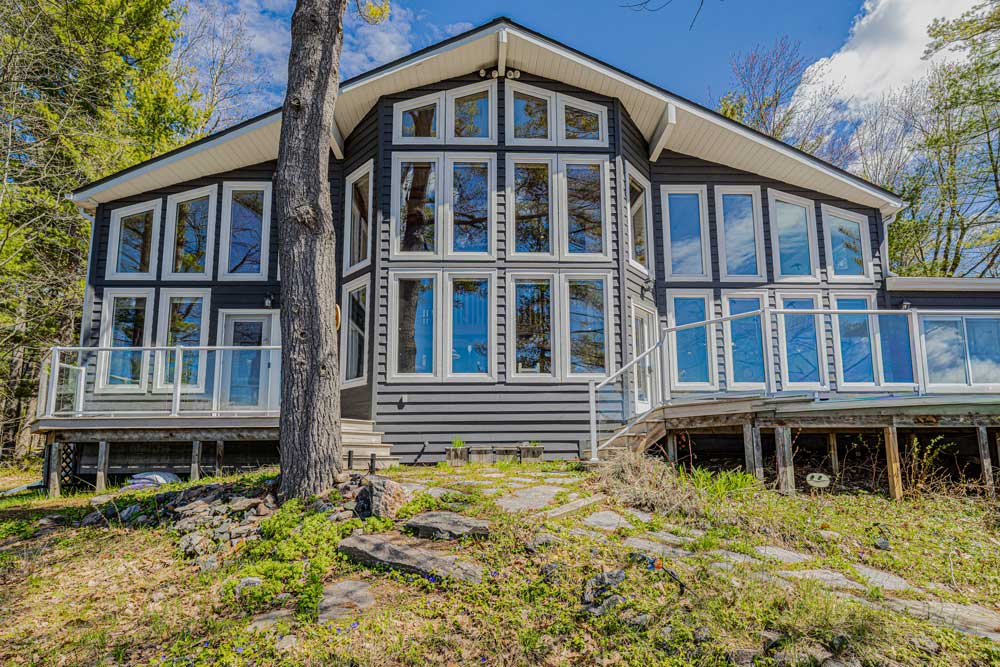 Exterior of a restored cottage on Loon Lake in Gravenhurst Ontario with completed roof assembly and Muskoka lakeside setting